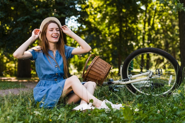 Frau, die auf Gras nahe bei Fahrrad sitzt