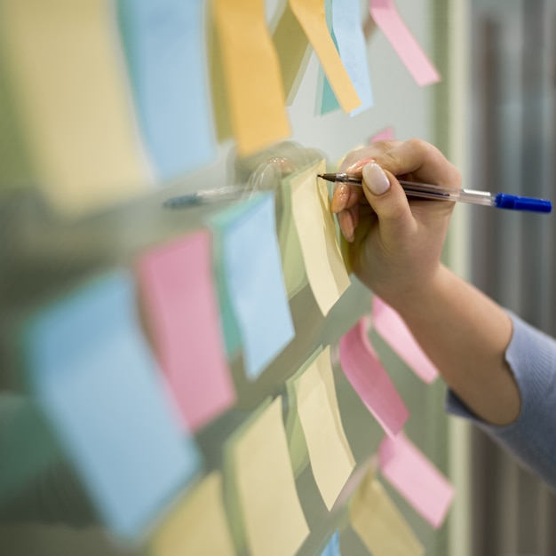 Frau, die auf Haftnotizen auf Bürofenster schreibt