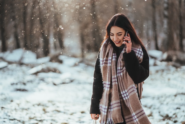 Frau, die auf Handy in kaltem Wintertag spricht.