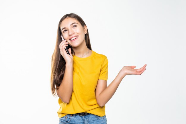 Frau, die auf ihrem Handy über einer weißen Wand spricht