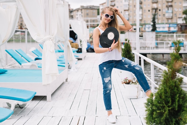 Frau, die auf Pier mit Vinylaufzeichnungen steht