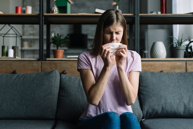 Frau, die auf Schlagnase des Sofas mit Seidenpapier sitzt