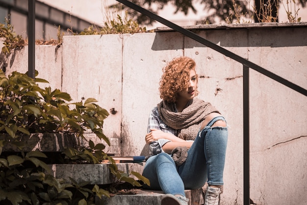 Frau, die auf Schritten nahe Garten der Bücher öffentlich sitzt