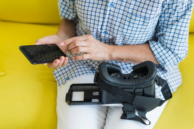 Frau, die auf Sofa unter Verwendung des Handys mit virtueller Kamera auf ihrem Schoss sitzt