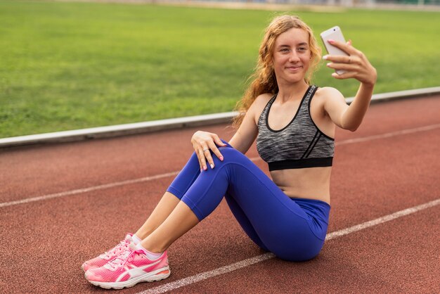 Frau, die auf Stadion sitzt und selfie nimmt