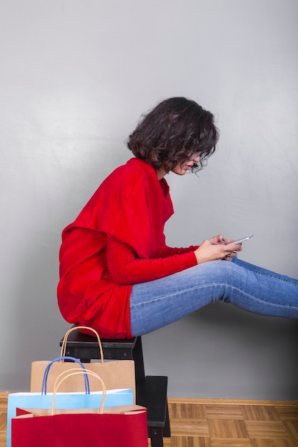 Kostenloses Foto frau, die auf stuhl mit smartphone sitzt