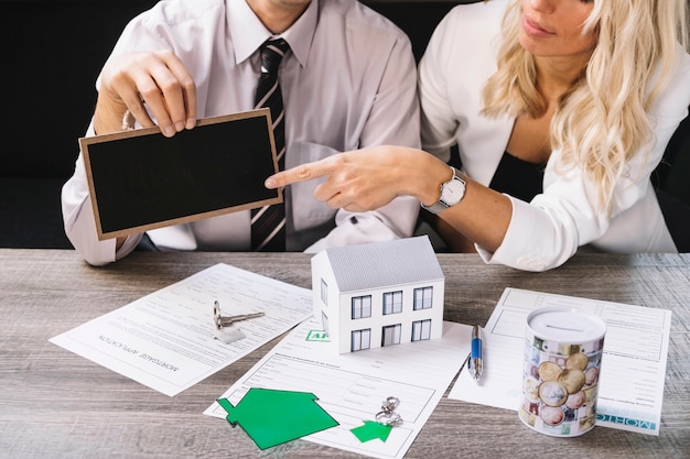 Frau, die auf Tafel in der Immobilienagentur zeigt