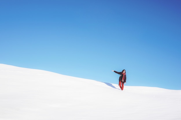 Kostenloses Foto frau, die auf weißem schneefeld während des tages steht