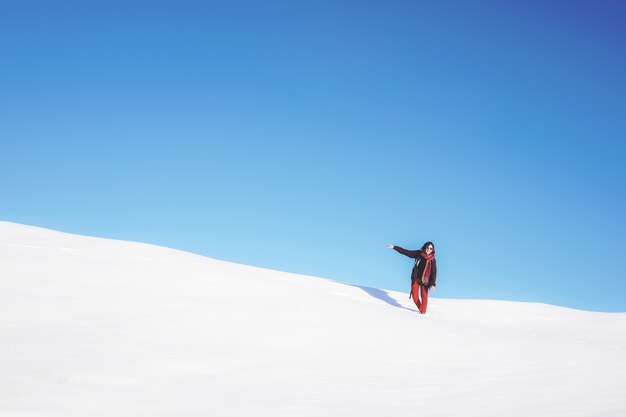 Frau, die auf weißem Schneefeld während des Tages steht