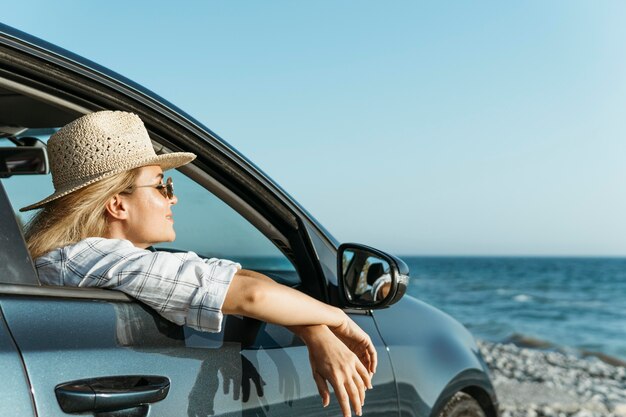 Frau, die aus Autofenster schaut, das Meer betrachtet