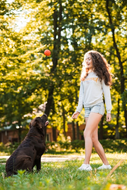 Frau, die Ball mit ihrem Hund im Garten spielt