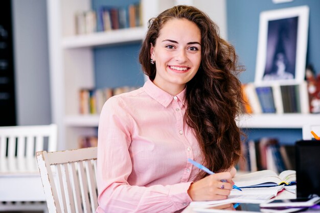 Frau, die bei Tisch mit Stift sitzt