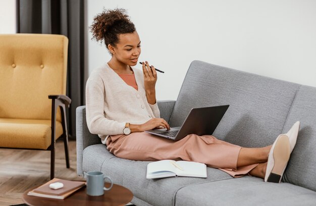 Frau, die beim Sitzen auf dem Sofa arbeitet