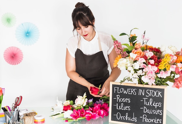 Frau, die Blumen mit Schiefer auf Glasschreibtisch sortiert