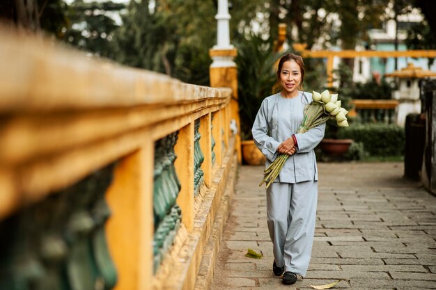 Frau, die Blumenstrauß am Tempel hält