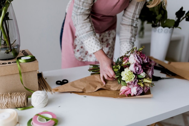 Frau, die Blumenstrauß einwickelt und anordnet