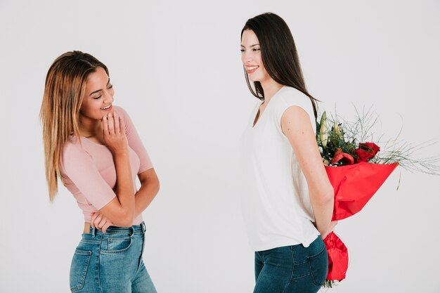 Frau, die Blumenstrauß für Freundin hinter Rückseite hält