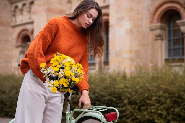 Frau, die Blumenstrauß hält, während er neben Fahrrad sitzt