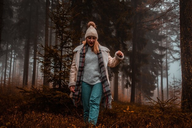 Frau, die braune Strickmütze im Wald trägt