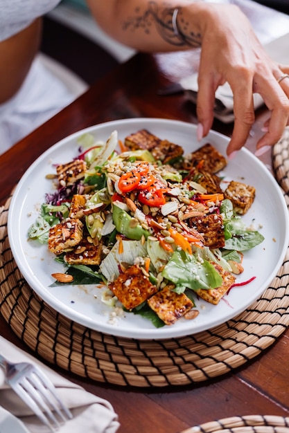 Frau, die bunte gesunde vegane vegetarische Mahlzeit Salat im Sommercafé natürliches Tageslicht hat