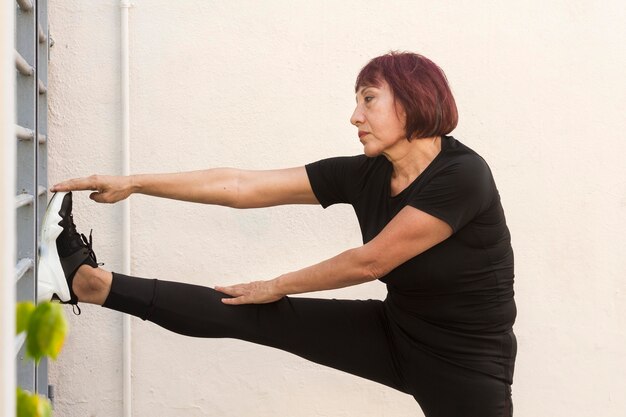 Frau, die Cardio tut und mit einem Bein an der Wand lehnt