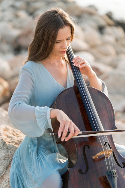 Frau, die Cello auf Felsen spielt