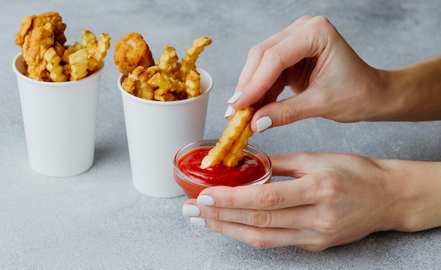 Frau, die Chips in Ketchup eintaucht