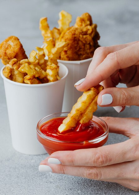 Frau, die Chips in Ketchup-Soße eintaucht