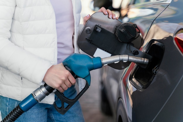 Frau, die das Auto an der Tankstelle auffüllt