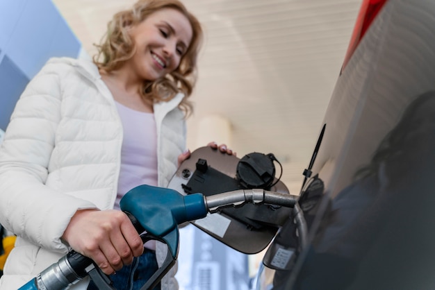 Frau, die das Auto an der Tankstelle auffüllt