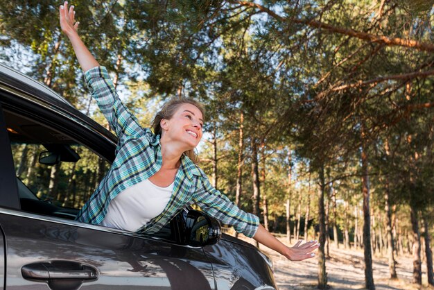 Kostenloses Foto frau, die das auto reitet und ihre hände in der luft hält