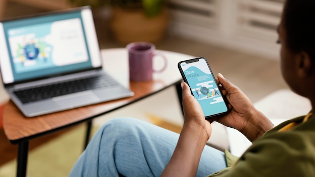 Kostenloses Foto frau, die das haus mit smartphone und laptop neu dekoriert