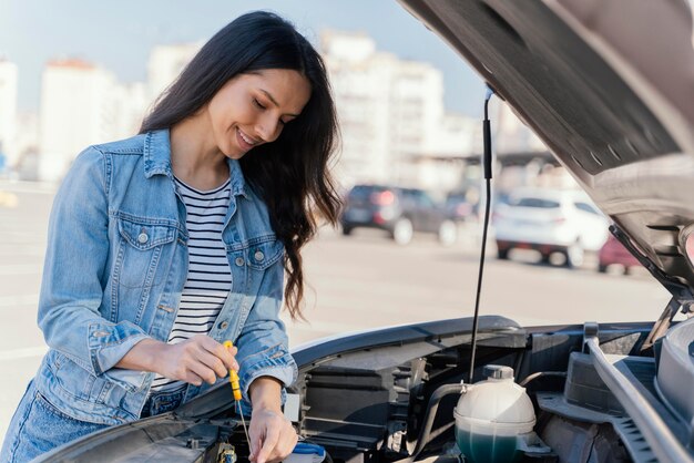 Frau, die das Öl ihres Autos prüft