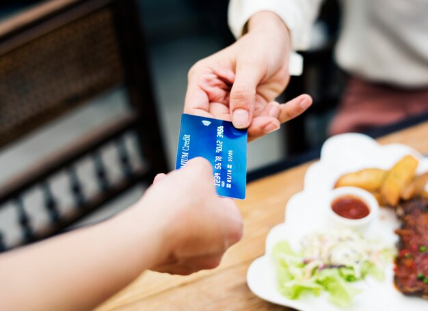 Frau, die das Mittagessen mit Kreditkarte am Restaurant zahlt