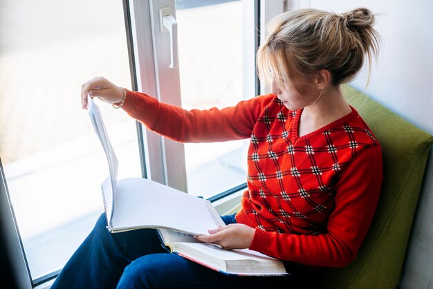 Frau, die das Sitzen nahe Fenster studiert