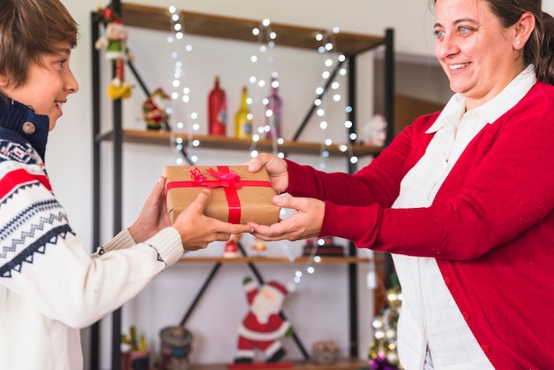 Frau, die dem Jungen Geschenkbox gibt