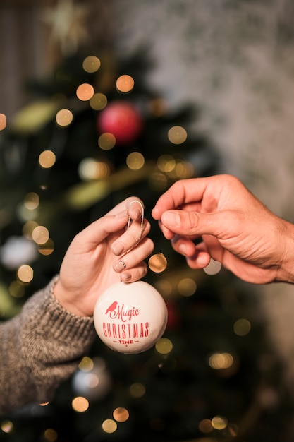 Frau, die dem Mann Verzierung Weihnachtskugel gibt