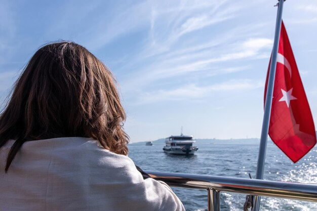 Frau, die den Blick auf das Boot genießt, das auf dem Schwarzen Meer in der Nähe der roten Flagge der Türkei schwimmt