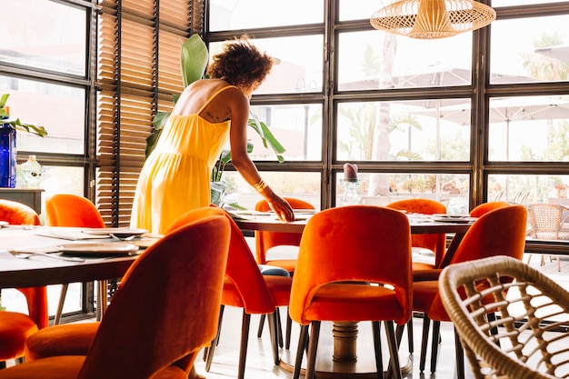 Frau, die den Dishware auf Tabelle im Restaurant vereinbart