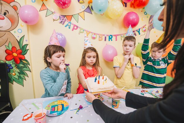 Frau, die den Kindern Geburtstagskuchen gibt