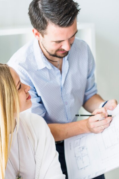 Frau, die den männlichen Architekten arbeitet an Plan betrachtet