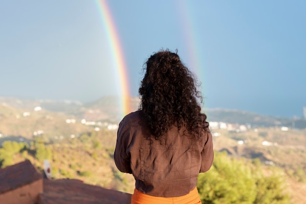 Frau, die den Regenbogen während der Party im Freien betrachtet