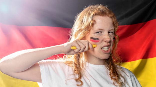 Frau, die deutsche flagge auf ihrem gesicht malt