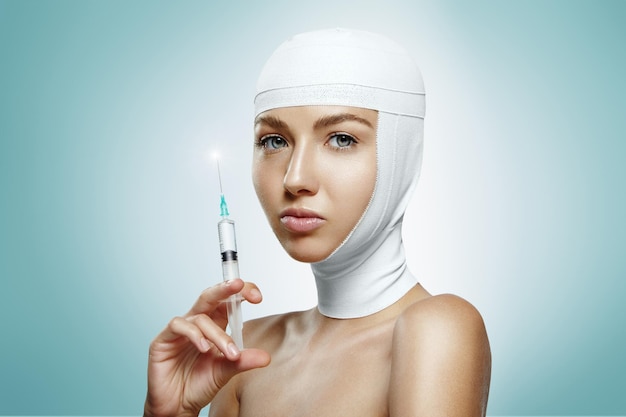 Frau, die die Botox-Injektion mit bandagiertem Kopf hält