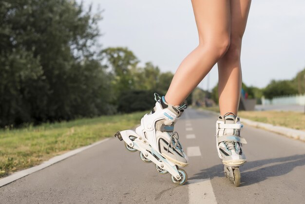 Frau, die die Rollschuhe trägt und auf dem Boden steht