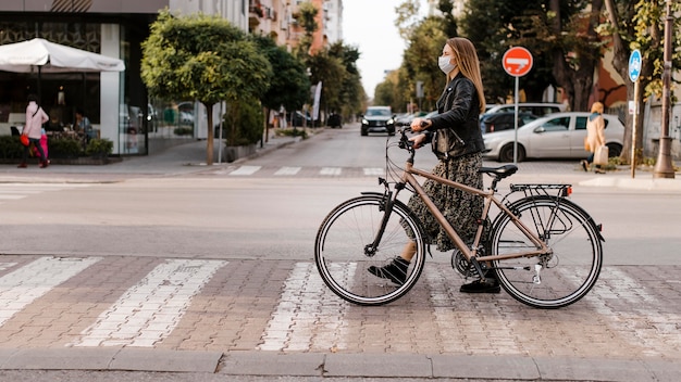 Frau, die die Straße neben ihrem Fahrrad überquert