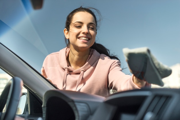 Kostenloses Foto frau, die die vordere windschutzscheibe an ihrem auto reinigt