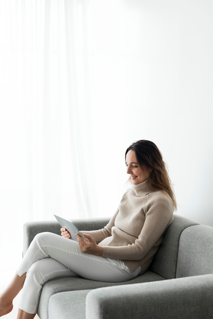 Frau, die digitales Tablett auf einer Couch verwendet