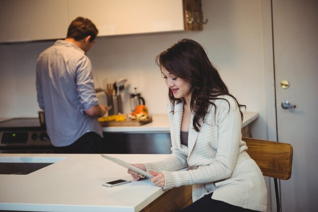 Frau, die digitales Tablett verwendet, während Mann im Hintergrund arbeitet