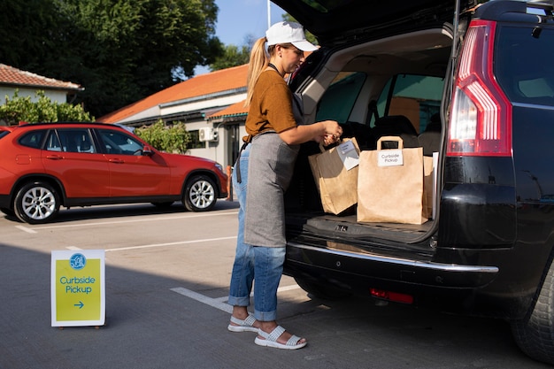 Frau, die draußen bei einer Abholung am Straßenrand eine Bestellung aufgibt